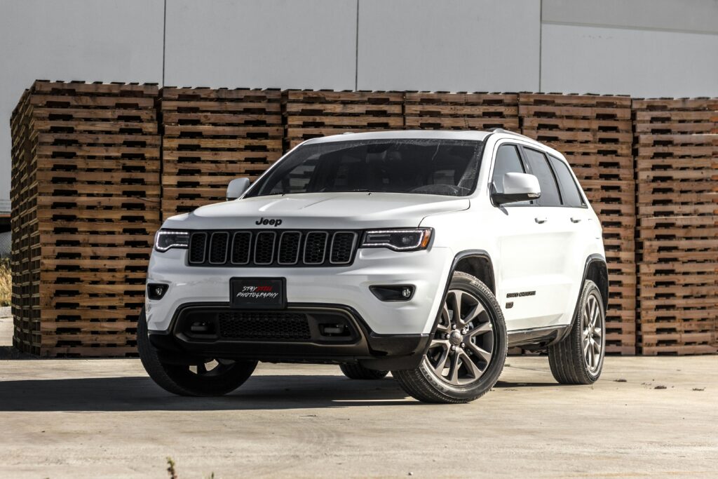 pexels photo 119435 119435 A sleek white Jeep Grand Cherokee parked in front of stacked wooden pallets, showcasing its luxury features.